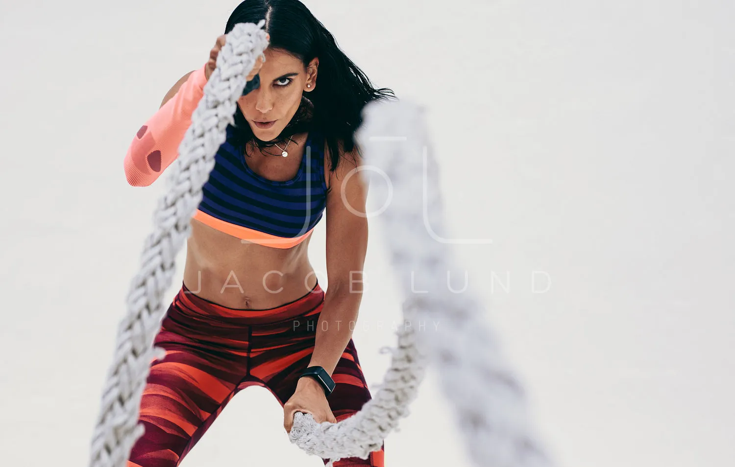Close up of a fitness woman working out using battle ropes
